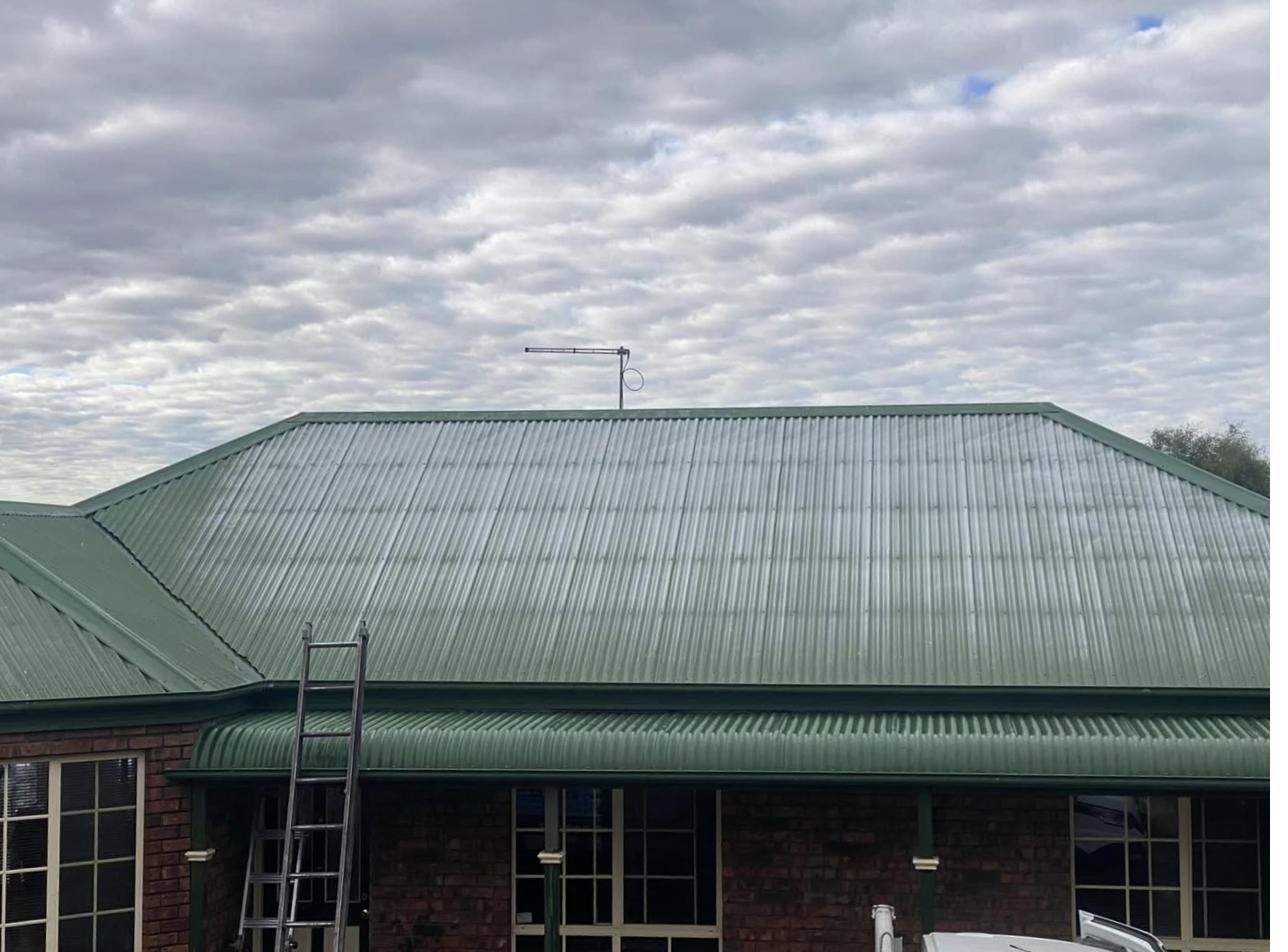 Faded oxidised green corrugated metal roof on a brick country home in Tasmania