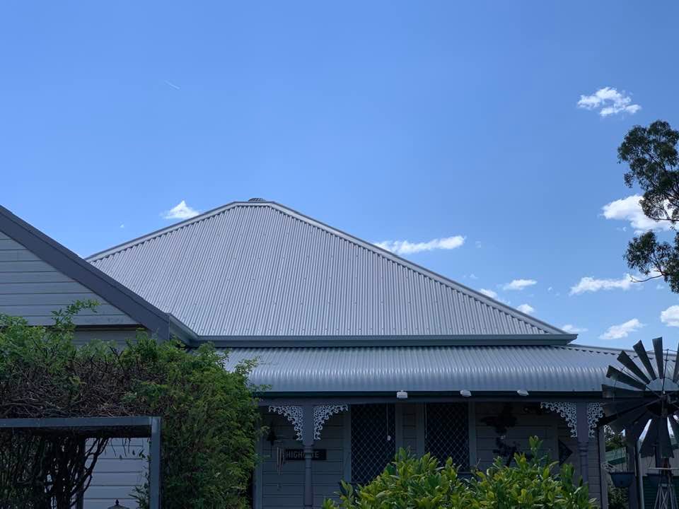 Red brick home with mid-grey roof beside lawn